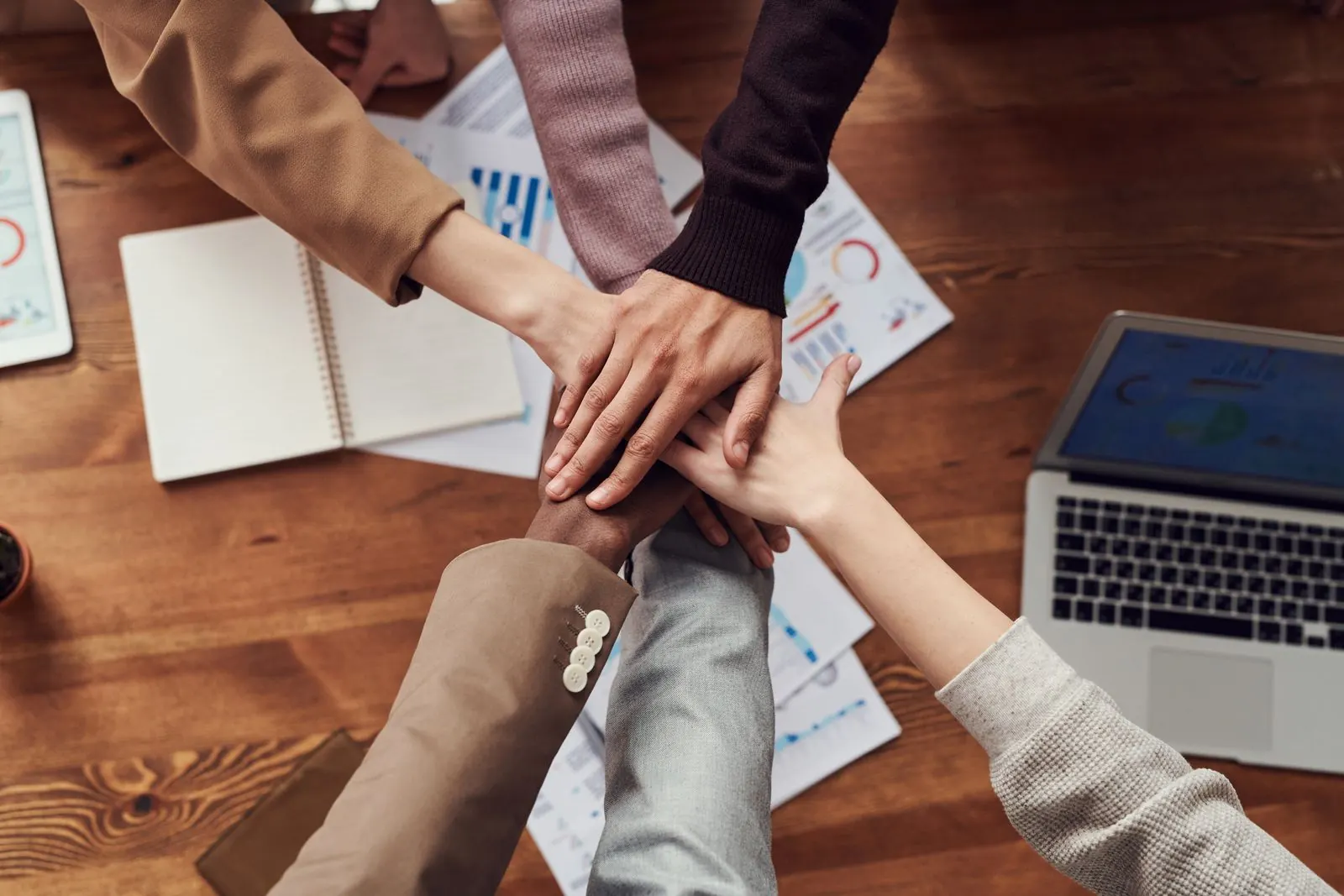 A team stacking their hands together over a table after a working session.